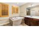 Bright bathroom features a soaking tub, wood-look tile, dual windows with privacy shutters and a vanity with white countertop at 9096 Becket Ranch Ct, Las Vegas, NV 89113