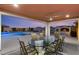 Covered patio with ceiling fan, dining table, and view of the outdoor kitchen and sparkling blue pool at 9096 Becket Ranch Ct, Las Vegas, NV 89113