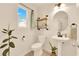 Stylish half bathroom featuring a pedestal sink, industrial shelving, and a large window for natural light at 9926 Swimming Hole St, Las Vegas, NV 89183