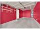 Well-lit garage with red walls, epoxy flooring, and built-in storage racks, perfect for organization and convenience at 9926 Swimming Hole St, Las Vegas, NV 89183