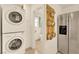 Convenient laundry area with stacked washer and dryer, adjacent to pantry storage and stainless refrigerator at 9926 Swimming Hole St, Las Vegas, NV 89183