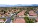 Aerial view showcasing a neighborhood with single-story homes, red tile roofs, lush landscaping, and distant mountain views at 10201 Los Padres Pl, Las Vegas, NV 89134
