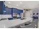 A modern kitchen featuring custom blue cabinets, stainless steel appliances, and elegant white marble countertops at 10201 Los Padres Pl, Las Vegas, NV 89134
