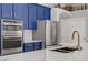 A view of a modern kitchen featuring custom blue cabinets, stainless steel appliances, and marble countertops at 10201 Los Padres Pl, Las Vegas, NV 89134