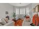 Cozy living room featuring neutral furniture, bright windows with shutters, and an eye-catching orange rug at 10201 Los Padres Pl, Las Vegas, NV 89134