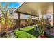 This covered backyard has an artificial lawn, potted plants, and comfortable seating at 10987 Kingston Fields Ave, Las Vegas, NV 89166