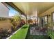 This covered backyard has an artificial lawn, potted plants, and comfortable seating at 10987 Kingston Fields Ave, Las Vegas, NV 89166