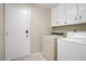 A dedicated laundry room featuring a washer and dryer set and storage cabinets at 1709 Autumn Rust Dr, Las Vegas, NV 89119