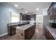 Well-lit kitchen features dark cabinetry, stone island, and stainless steel appliances at 4440 Pacific Crest Ave, Las Vegas, NV 89115