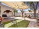 Serene backyard space with artificial grass, covered patio, shade sail, and a charming fire pit at 5325 Sandstone Dr, Las Vegas, NV 89142