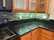 Kitchen counter and backsplash featuring black stone counters, mosaic backsplash, and wood cabinets at 5425 Whisper Bluff St, North Las Vegas, NV 89031