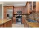 Kitchen featuring a stainless-steel refrigerator, gas range, granite countertops, tile backsplash, and ample cabinet space at 6 Via Vasari # 105, Henderson, NV 89011