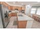 Eat-in kitchen showcases an island with bar seating, stainless steel refrigerator, and natural wood cabinetry at 6630 Cave Rock Ave, Las Vegas, NV 89110