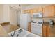 Functional kitchen with white appliances, wooden cabinets, and a view of the attached breakfast area at 10550 W Alexander Rd # 2017, Las Vegas, NV 89129
