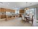 Well-lit kitchen with wood cabinetry, an island with granite countertops, stainless appliances, and an adjacent dining area at 1264 Olivia Pkwy, Henderson, NV 89011