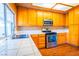 Well-lit kitchen featuring wood cabinets, stainless steel appliances, and white tiled countertops at 1309 Misty View Ct, North Las Vegas, NV 89031