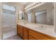 Bathroom featuring double sinks, cabinets, a large mirror, and a separate tub with white tiling at 1335 Heather Oaks Way, North Las Vegas, NV 89031