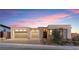Contemporary home featuring a three-car garage, stylish brick accents, and professionally landscaped front yard at twilight at 144 Tre Pietre St, Henderson, NV 89011