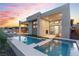 Stunning modern home showcasing a luxurious pool with integrated spa and a spacious outdoor living area at dusk at 144 Tre Pietre St, Henderson, NV 89011
