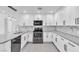Modern kitchen features white cabinetry, stainless steel appliances, gray quartz countertops and marble backsplash at 244 N 19Th St, Las Vegas, NV 89101