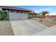 A wide driveway leading to an attached two-car garage, surrounded by desert landscaping and a red tile roof at 291 Lido Dr, Henderson, NV 89015