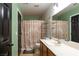 Bathroom with green walls, vanity, shower, and dark wood door at 6636 Brent Scott St, North Las Vegas, NV 89086