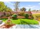 Manicured backyard with lush, artificial turf, manicured garden beds, and relaxing fountain at 7505 Mission Palm St, Las Vegas, NV 89139