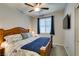 A cozy bedroom with a wooden bed frame, ceiling fan, and a window with blue curtains at 7553 Old Compton St, Las Vegas, NV 89166