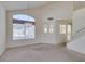 Spacious living room featuring large windows, a chandelier, and access to a staircase at 8012 Pottery Creek Dr, Las Vegas, NV 89128