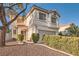 Stucco home featuring a red front door, two-car garage and manicured front yard with a tree at 8476 Tackle Box Ct, Las Vegas, NV 89113