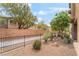Backyard featuring rock landscaping, trees, bushes, and a sidewalk at 8942 Partridge Hill St, Las Vegas, NV 89148