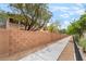 Exterior view of the townhomes, sidewalk, trees, and brick wall at 8942 Partridge Hill St, Las Vegas, NV 89148