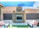 Close-up of a stucco fireplace with a decorative clock and seating area in a backyard at 8942 Partridge Hill St, Las Vegas, NV 89148