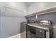 This laundry room features modern gray washer and dryer units, and shelving for storage at 8942 Partridge Hill St, Las Vegas, NV 89148