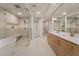 Bright bathroom featuring double sink vanity, soaking tub, glass-enclosed shower, and modern fixtures at 9101 Alta Dr # 207, Las Vegas, NV 89145