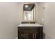 Close-up of the powder room vanity with a black cabinet, marble countertop, gold accents, and textured wallpaper at 9101 Alta Dr # 207, Las Vegas, NV 89145