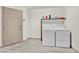 Neat laundry room with front-loading washer and dryer, storage shelf, and tiled flooring at 9830 Wild Coyote Ct, Las Vegas, NV 89141