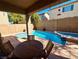 Picturesque backyard boasts a sparkling pool, hot tub, covered patio, stone retaining wall, and outdoor dining set at 1011 Pecos River Ave, Henderson, NV 89002