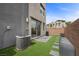 A modern backyard features faux grass, patio, AC unit and a brick wall at 11325 Gravitation Dr, Las Vegas, NV 89135