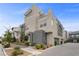 Contemporary three-story townhome with a balcony, attached garage, and manicured landscaping on a sunny day at 11325 Gravitation Dr, Las Vegas, NV 89135