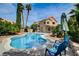 Relaxing backyard oasis with a swimming pool, spa, patio seating, and lush tropical landscaping at 2401 Rice Flower Cir, Las Vegas, NV 89134