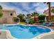 Inviting backyard featuring a sparkling pool, manicured lawn, basketball hoop, and seating area for relaxation and recreation at 2401 Rice Flower Cir, Las Vegas, NV 89134