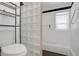 Well-lit bathroom with a glass block partition, white tile, and black accents at 2706 Colanthe Ave, Las Vegas, NV 89102