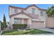 Front exterior of a two-story home featuring a well-kept lawn, garage, and decorative landscape at 319 Fox Lake Ave, Las Vegas, NV 89148