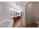 Bathroom with dual sinks, soaking tub, and wood-look flooring at 3439 Cottage Canyon St, Laughlin, NV 89029
