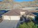 The home includes desert landscaping, a driveway, three-car garage, and a brown tile roof at 3439 Cottage Canyon St, Laughlin, NV 89029