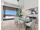 Modern dining room with a glass table, stylish white chairs, unique lighting, and a stunning view of the outdoors at 535 Serenity Point Dr, Henderson, NV 89012