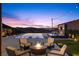 Outdoor seating area with a fire pit overlooking an infinity pool at dusk with city views at 535 Serenity Point Dr, Henderson, NV 89012