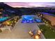 Expansive pool and spa area with lounge chairs, lush landscaping, ambient lighting, and serene hillside views at dusk at 535 Serenity Point Dr, Henderson, NV 89012