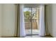 A view of the balcony, featuring sliding glass doors and neutral colored curtains with outside trees at 5751 E Hacienda Ave # 243, Las Vegas, NV 89122